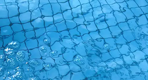 Surface d'eau de piscine avec reflets bleus et bulles